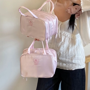 Dettaglio delle borse da trucco in raso rosa con ricamo a fiocco Lucky e manico