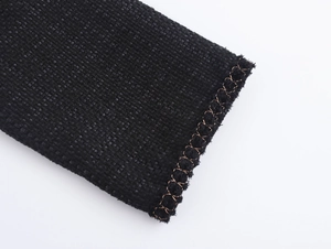 Vista macro dettagliata della trama in tweed nero con finitura dell'orlo a punto croce rame