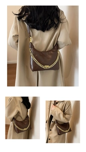 Detail of dark brown quilted shoulder bag featuring gold chain and trapezoid shape