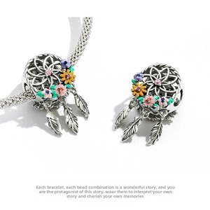 Macro detail of silver dreamcatcher bead with colorful enamel flowers and feather charms