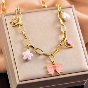 Pink enamel flower and butterfly bow golden charm necklace on silk background