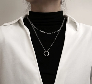 Detail of silver double layered necklace with ring pendant on a chic black turtleneck