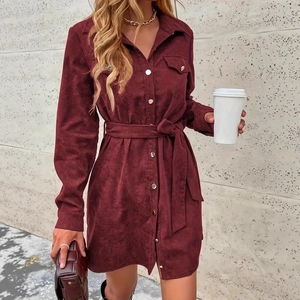 Detail of burgundy corduroy shirt dress showing button closure and waist tie