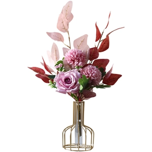Artificial pink roses and daisies in a modern gold metal wire and glass tube vase