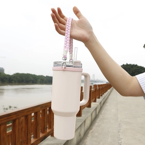 Close-up of pink 40oz insulated tumbler with a decorative pink and white paracord handle