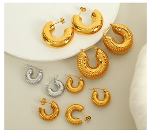 Close-up of assorted 18K gold and silver hoop earrings with textured metal surfaces