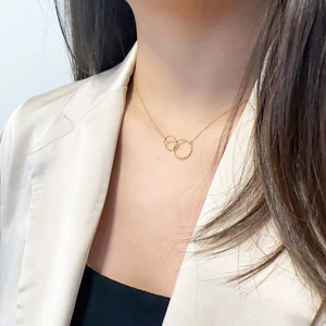 Minimalist double-loop titanium steel necklace in gold finish worn by female model