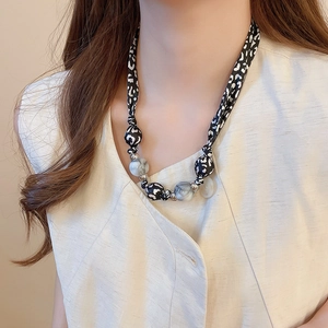 Détail de perles en tissu léopard et sphères marbrées sur un collier élégant pour femme