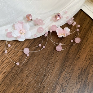 Detail of pink floral beaded long tassel earrings with silver needle on white fabric