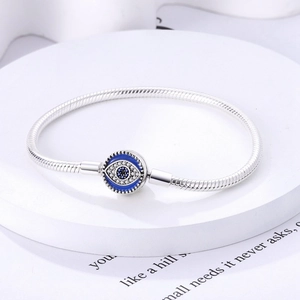 Silver snake chain bracelet featuring a blue evil eye charm with sparkling crystal accents