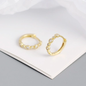 Macro shot of gold S925 silver hoop earrings with shimmering round clear cubic zirconia