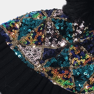 Detail of colorful sequins and black faux fur pom-pom on the knit beanie