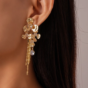 Detail view of gold flower earrings with sparkling tassels and water drop stones on a model