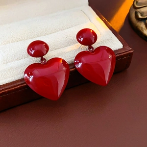Close-up of red heart pendant earrings in a premium jewelry box on beige lining