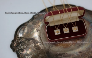 Close-up of golden bee pendant with square white shell inlay in a red jewelry box