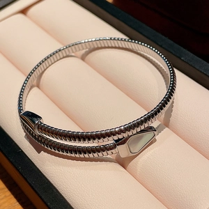 Macro shot of silver snake coil bracelet with mother of pearl inlay in a soft pink jewelry box