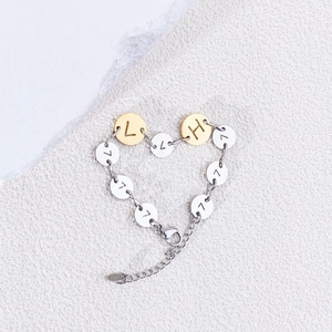 Dettaglio del bracciale in acciaio a cuore con ciondoli incisi L, H e il numero 7