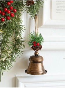 Macro detail of bronze Christmas bell with pine needles and red berries on hemp rope