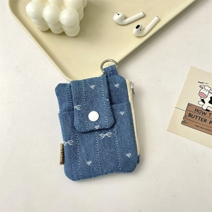 Detail of light blue denim card holder with white heart patterns and metal clip