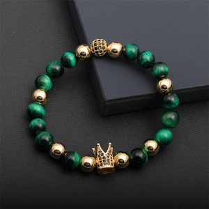 Close-up of green malachite beads and gold crown charm with black zircons on leather
