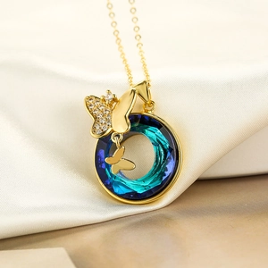 Goldene Halskette mit blauem Schmetterlingsanhänger auf beiger Seide