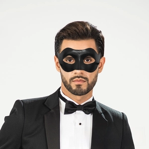 Close-up of a black faux leather masquerade eye mask worn by a male model in formal attire