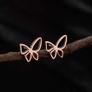Minimalist hollow butterfly stud earrings in rose gold on a natural branch
