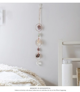Detail of amethyst and citrine suncatcher with rose gold rings on a white wall
