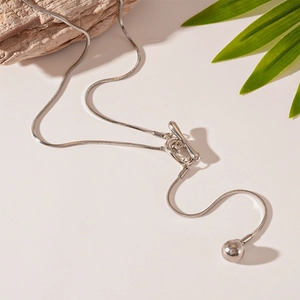Elegant silver snake chain necklace with OT buckle and round bead pendant on beige background