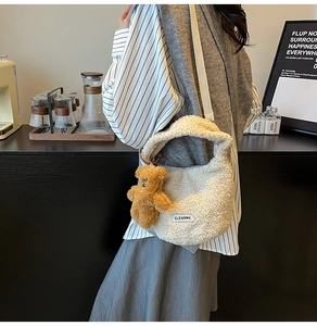 Detail of beige fleece bucket bag with cute bear charm and woven strap on a model