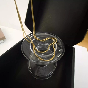 Close-up of 18K gold plated square snake bone chain necklace on a glass display stand