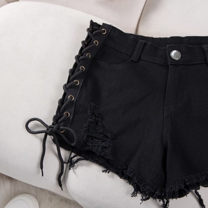 Dettaglio degli shorts in denim nero con lacci laterali e orlo grezzo sfilacciato
