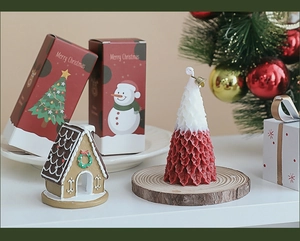 Close-up of a Christmas tree candle with a gingerbread house and festive gift packaging