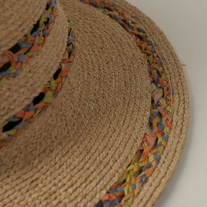 Macro shot of colorful woven raffia detailing on a natural handmade flat top straw hat