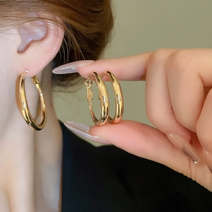 Close-up of chunky gold hoop earrings with high-polish finish on a female model