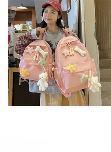 Close-up of pink nylon backpack with cute plush stars and a white bear charm detail