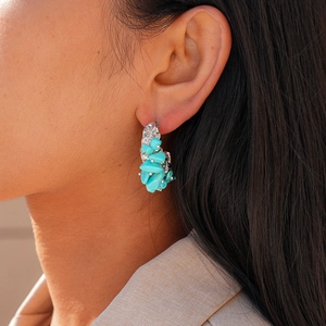 Detail of vintage silver C-shaped earrings with irregular turquoise stone inlay for women