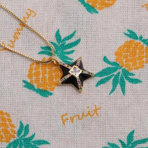 Detail of gold star necklace with colorful crystals on a fruit patterned textile background