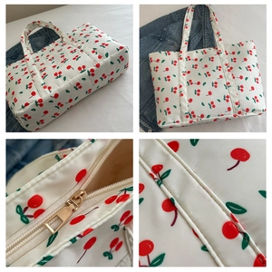 Close-up of white tote bag with red cherry patterns and smooth zipper detail