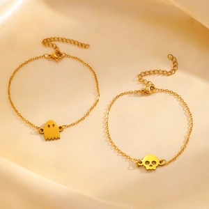 Golden stainless steel bracelets featuring hollow ghost and skull pendants on silk background