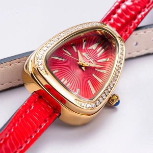 Close-up of golden snake head watch case with red dial and sparkling crystal bezel