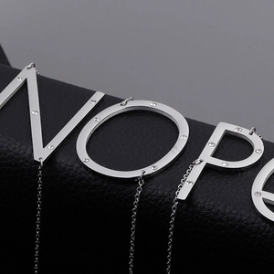 Silver alphabet pendant necklace with rhinestones N O P E on black leather background