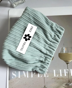 Detail of mint green corduroy pouch featuring a floral logo card and soft striped texture