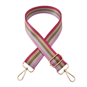 Macro detail of multi-color striped bag strap with premium gold metal swivel hooks