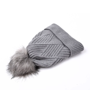 Detail of grey diamond-pattern knit beanie with a fluffy faux fur pompom and wide cuff