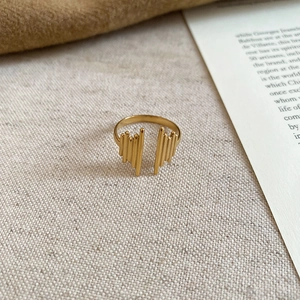 Detailed view of the gold hollow wavy lines open ring on a cream textured fabric background