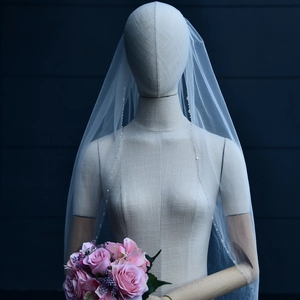 Detailed view of white bridal veil with delicate sequins on thin tulle and metal comb