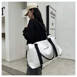 Outdoor shot of a minimalist white travel bag with black straps and XHUAYUNX logo detail