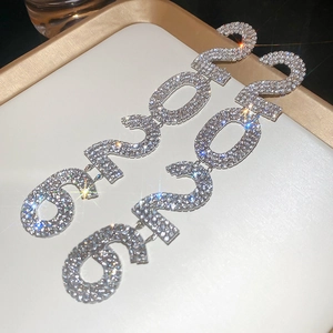 Detailed macro view of 2023 number earrings with sparkling rhinestones on a white tray