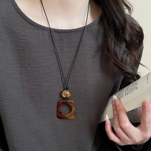Detailed view of resin leopard print square pendant necklace on a grey top background